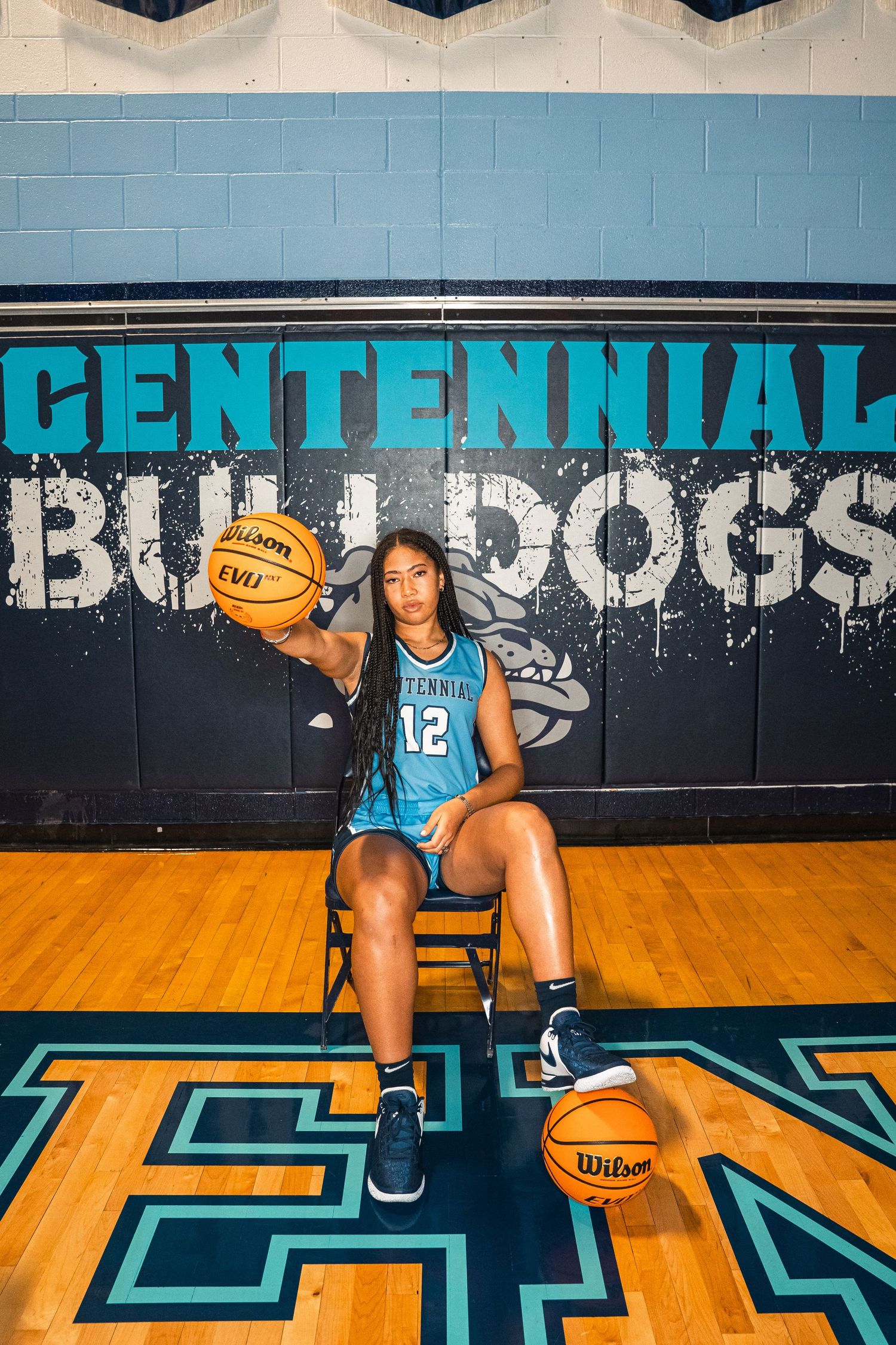 Basketball player in blue jersey displays ball-handling skills on gymnasium floor.