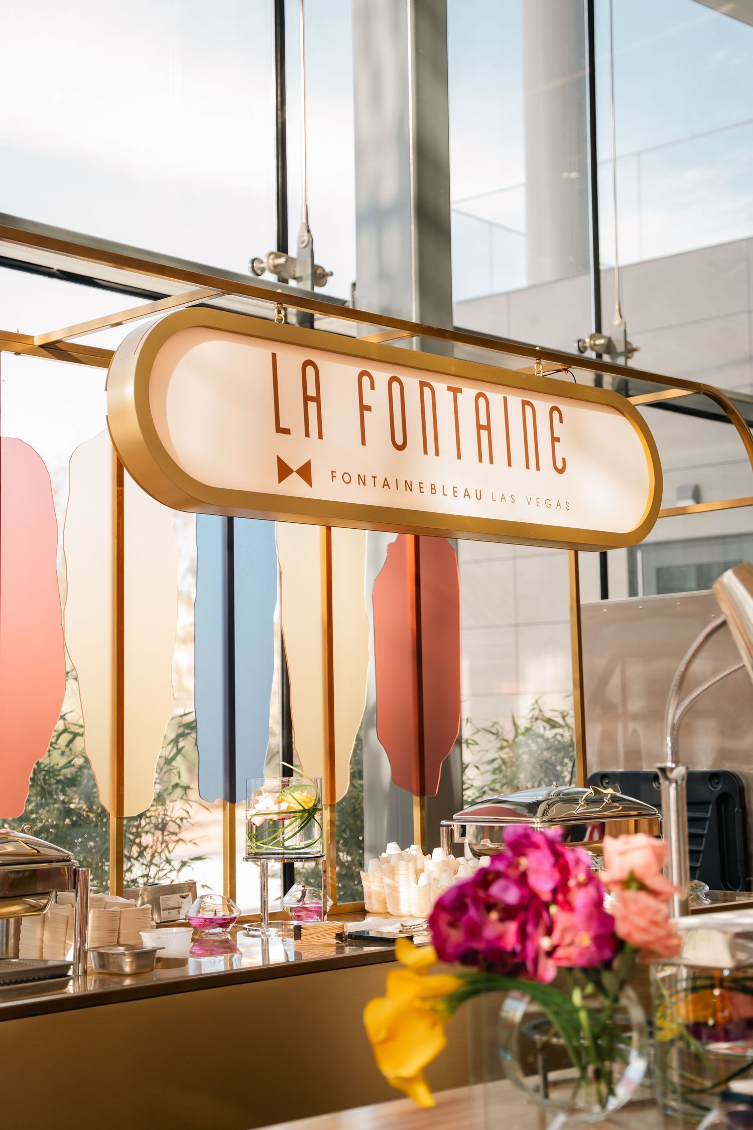 Elegant La Fontaine restaurant sign with fresh flowers and pastel decor.