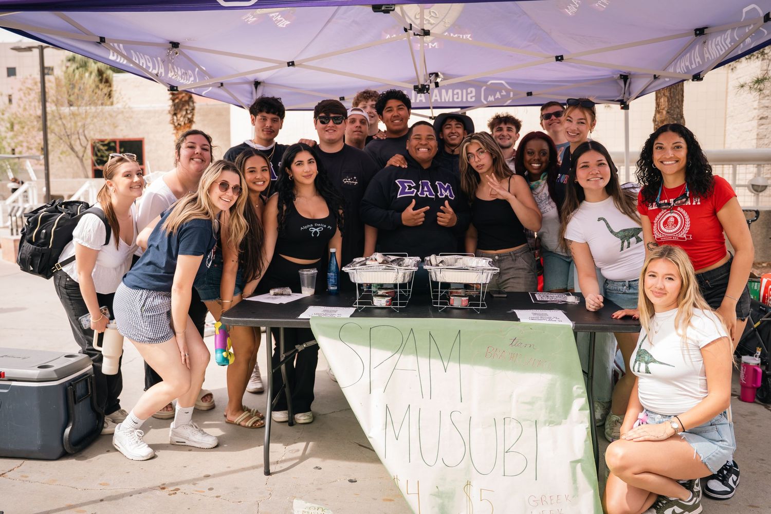 Students gather around a booth at an outdoor campus organization fair.