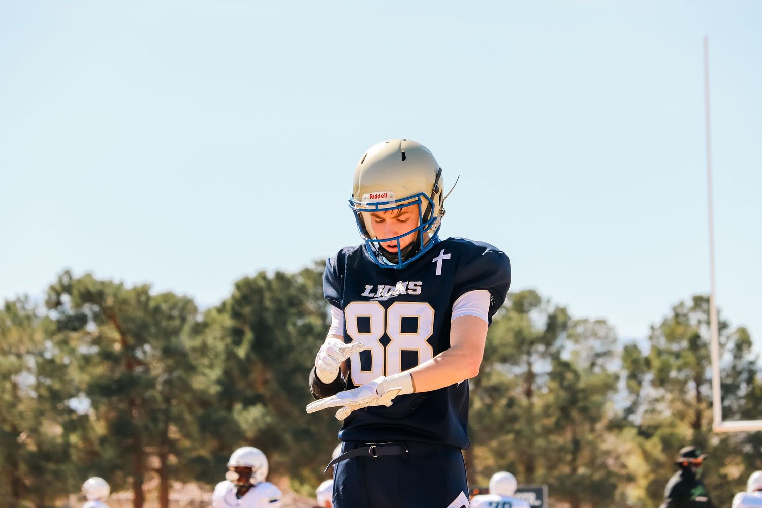 Football players in navy uniforms practicing on a sunny field.