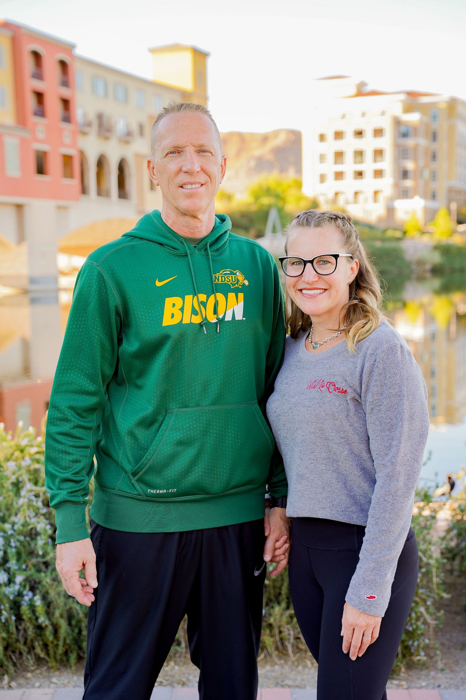 A duo wearing Bison and casual athletic wear pose together against a colorful urban backdrop.