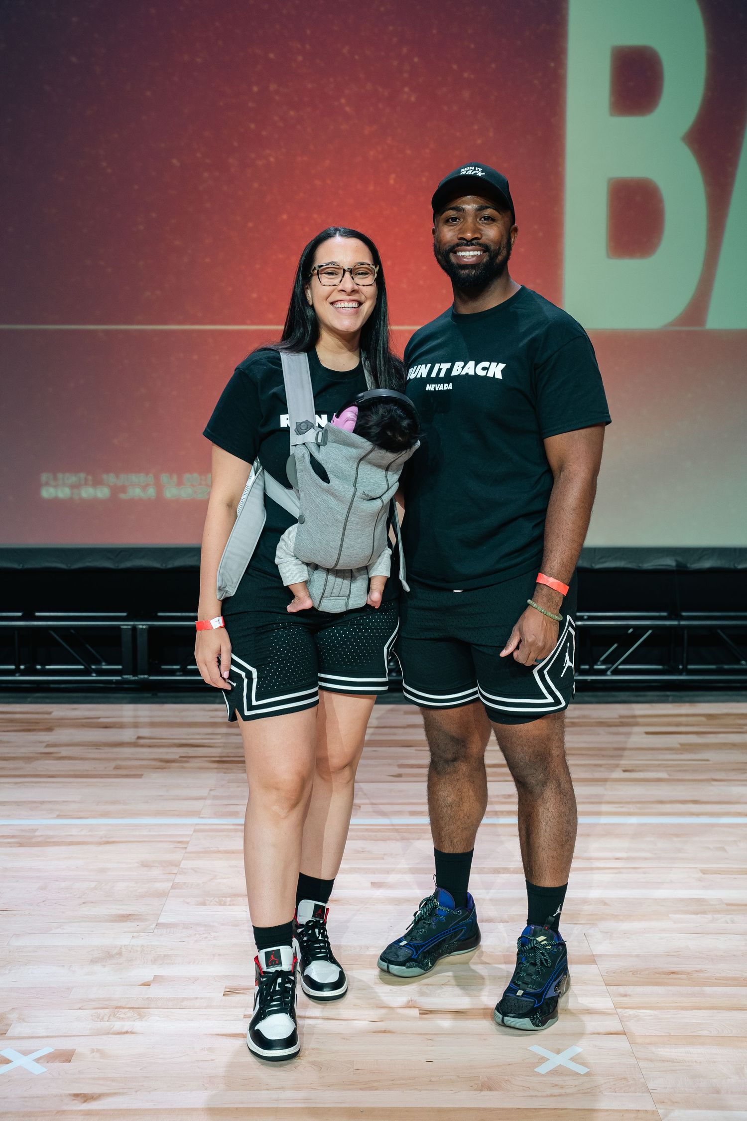 People in athletic wear posing together on a gym floor with markings.