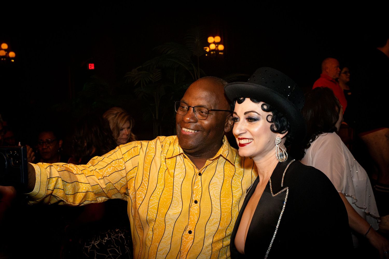 Audience members enjoying nightclub atmosphere under warm lighting.