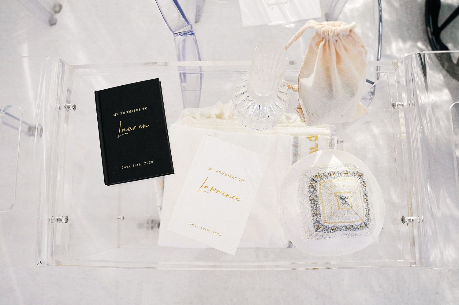 Luxury wedding accessories and stationery displayed in clear acrylic box.