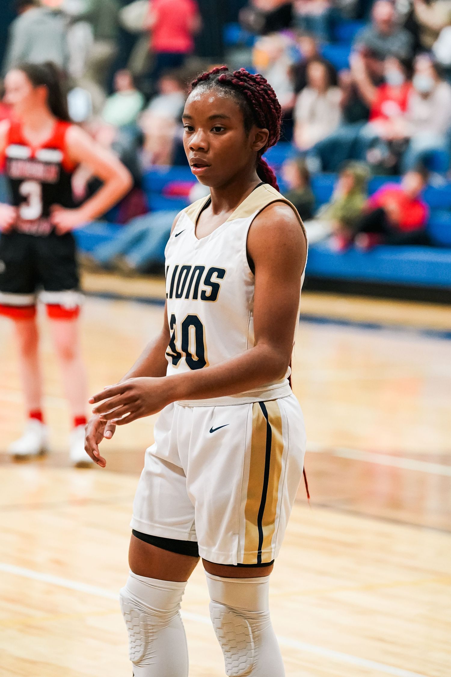 Basketball player in white Lions uniform standing ready during game.
