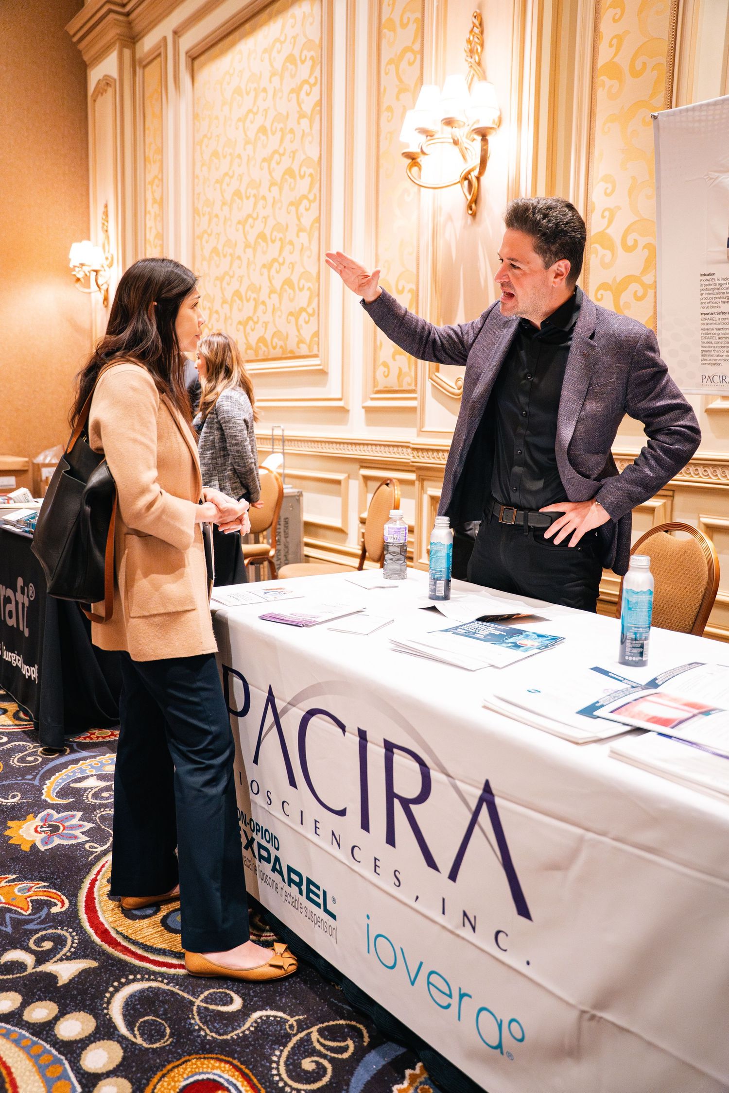 Business representatives engage in conversation at a Pacira branded table during a professional networking event.