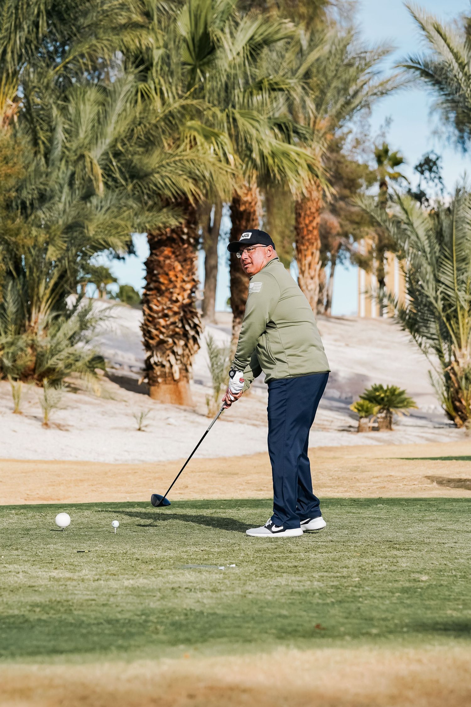 Golfer practicing their putting technique on a green with palm trees in the background.