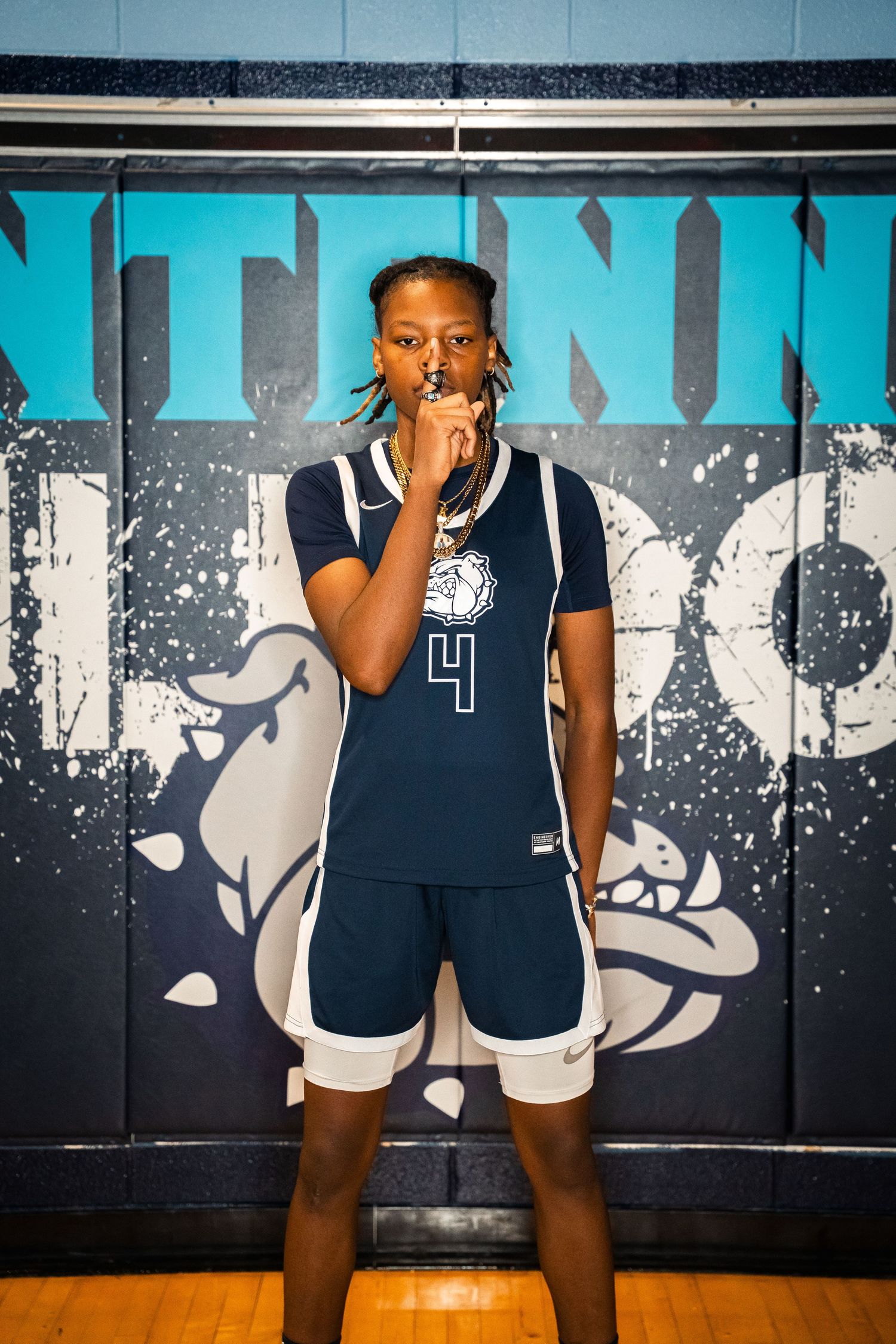 Basketball player in navy uniform posing with ball for team photo.