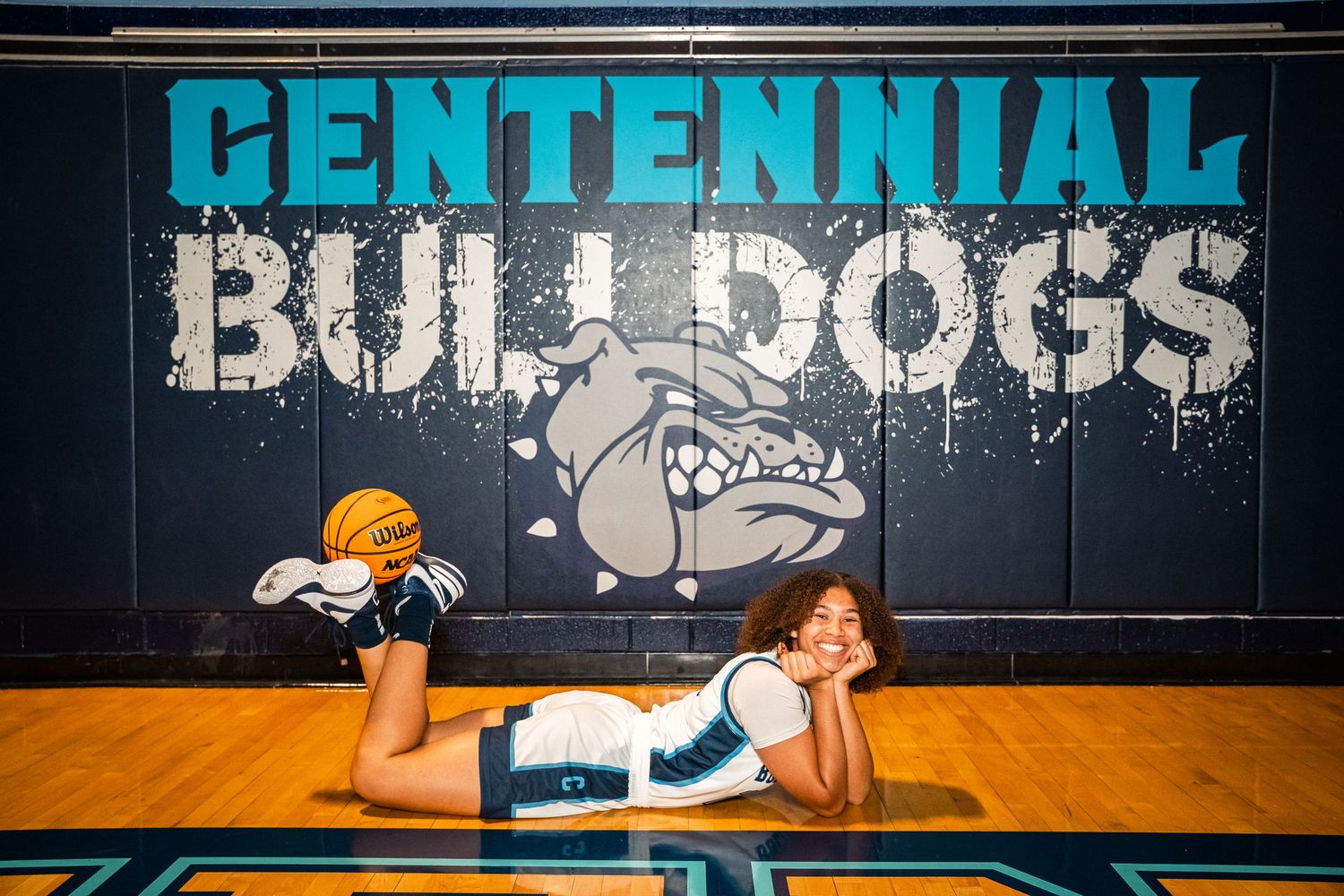 Basketball athlete performing stretches and drills on wooden court.