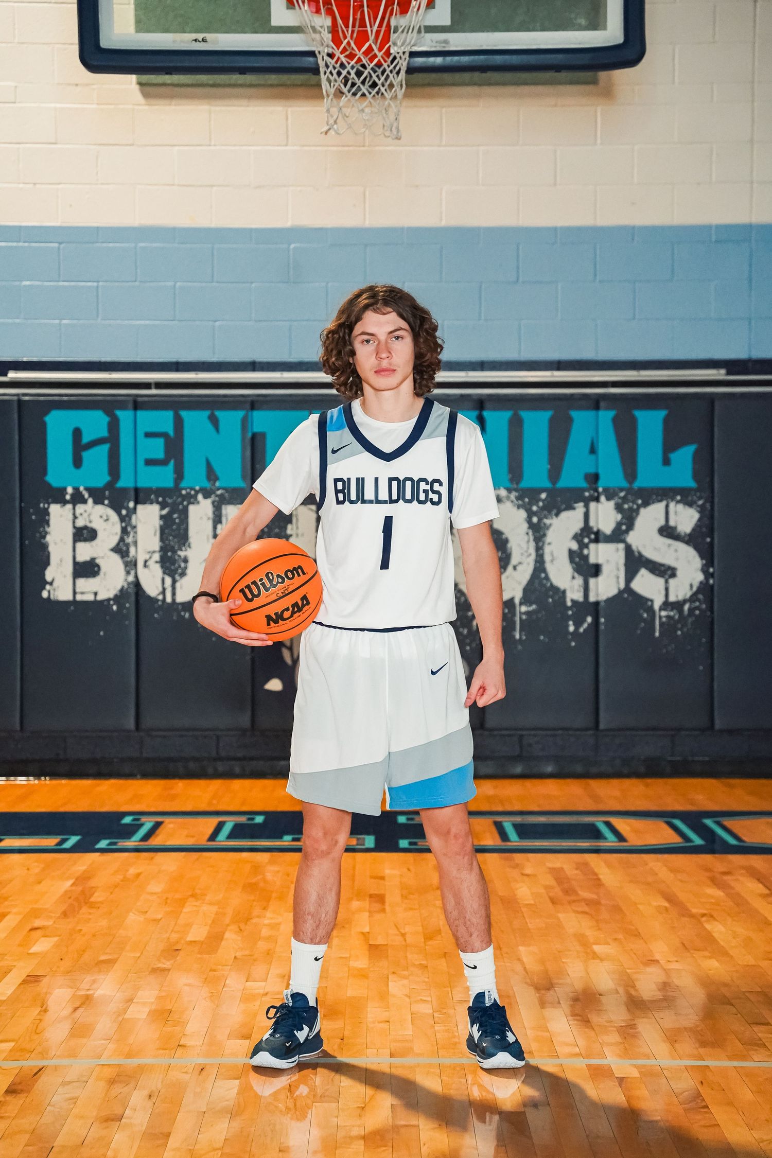 Basketball player in white Bulldogs jersey number 1 posing with ball on court.