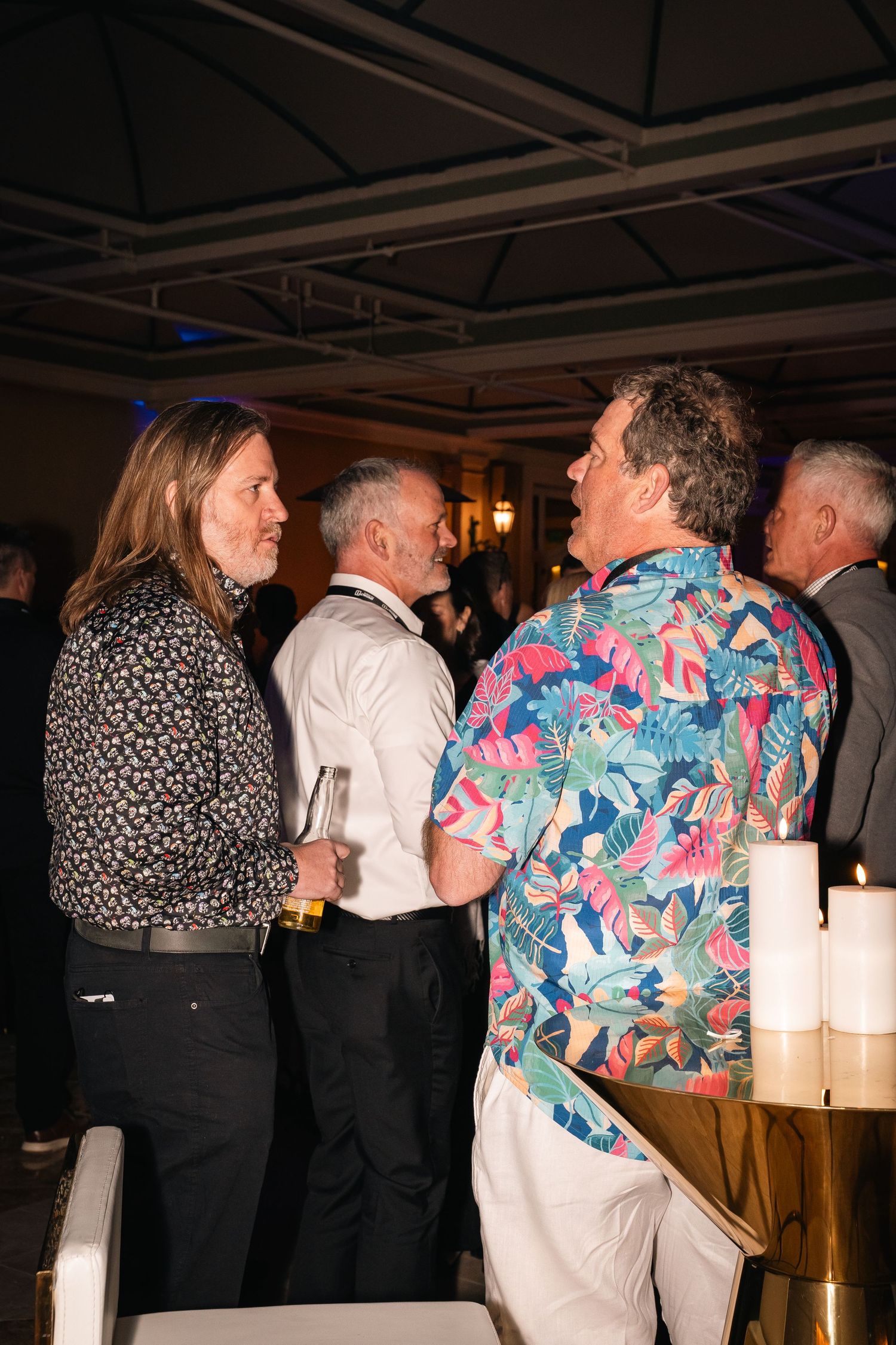 Evening party guests engaged in conversation near illuminated dining area.