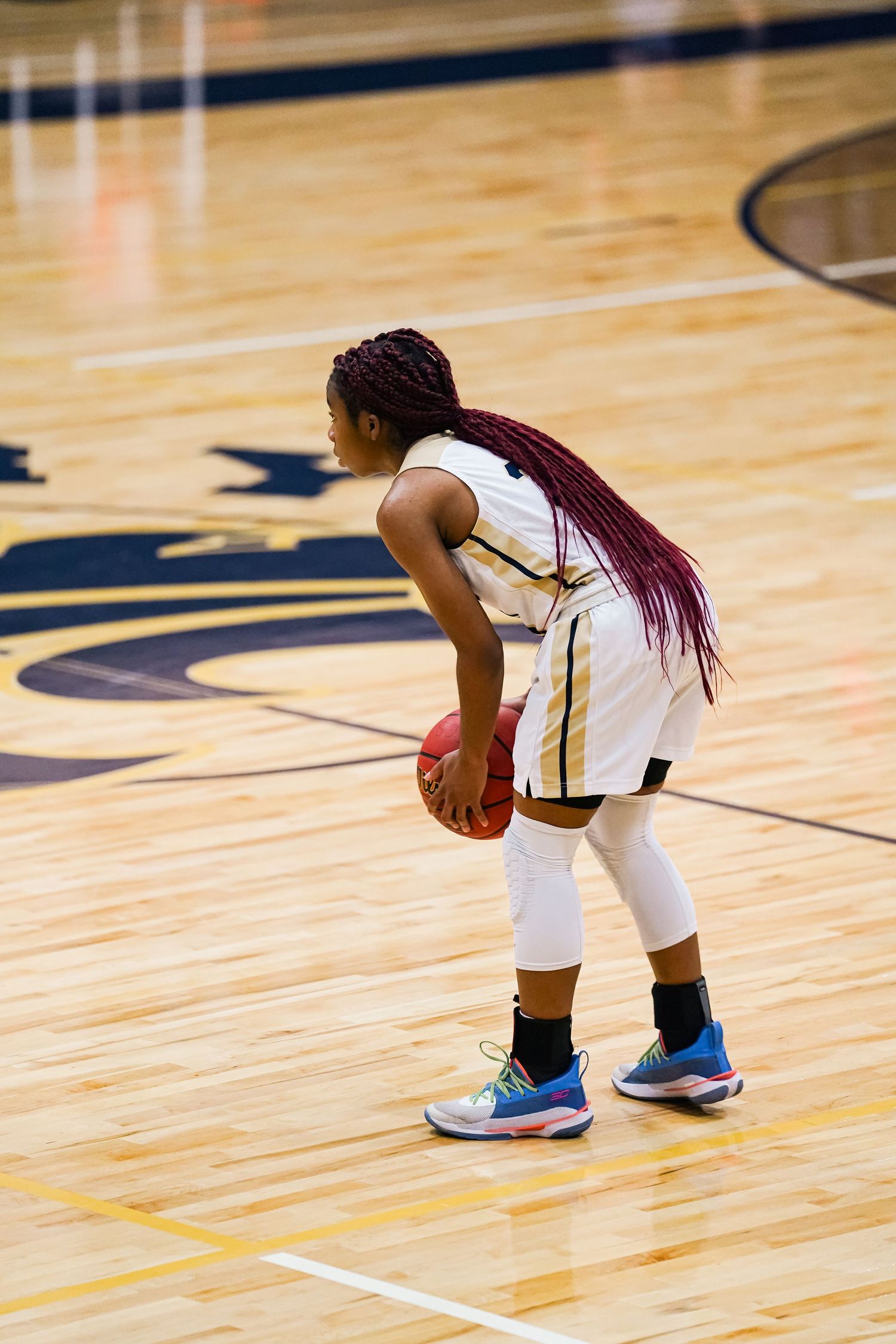Basketball player in white uniform prepares to make a play on the court.