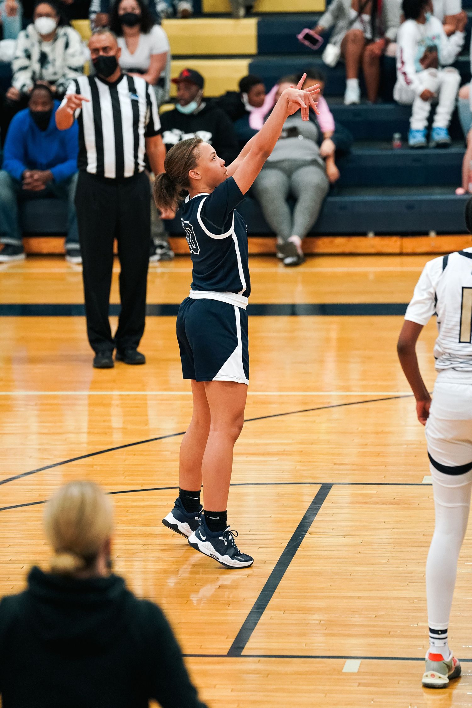 Players and officials stand on basketball court during game break.