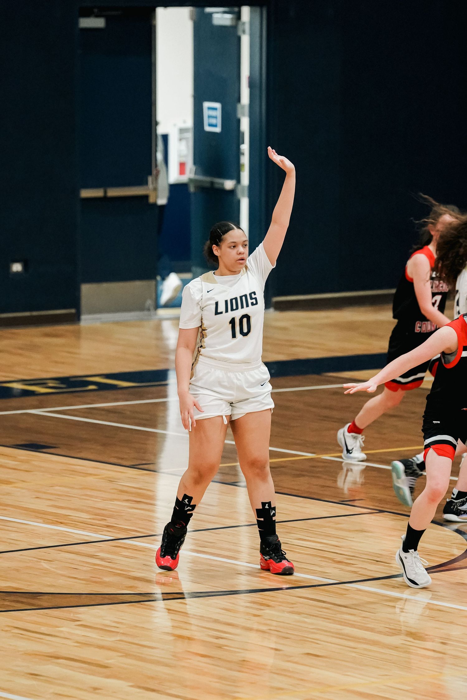 Basketball player in white Lions jersey signaling during game play.