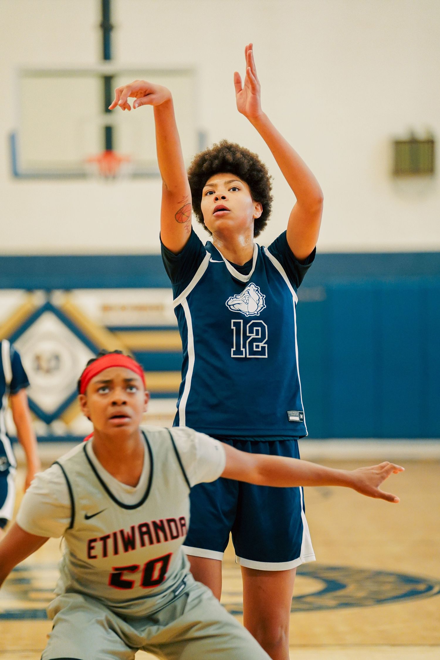 Basketball players from opposing teams jump for a rebound during competitive game action.