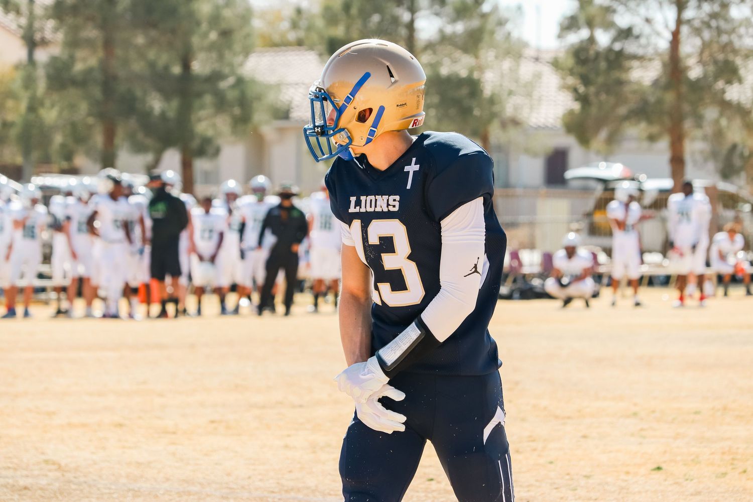 Football player in navy jersey number 8 standing on sunny field during game.
