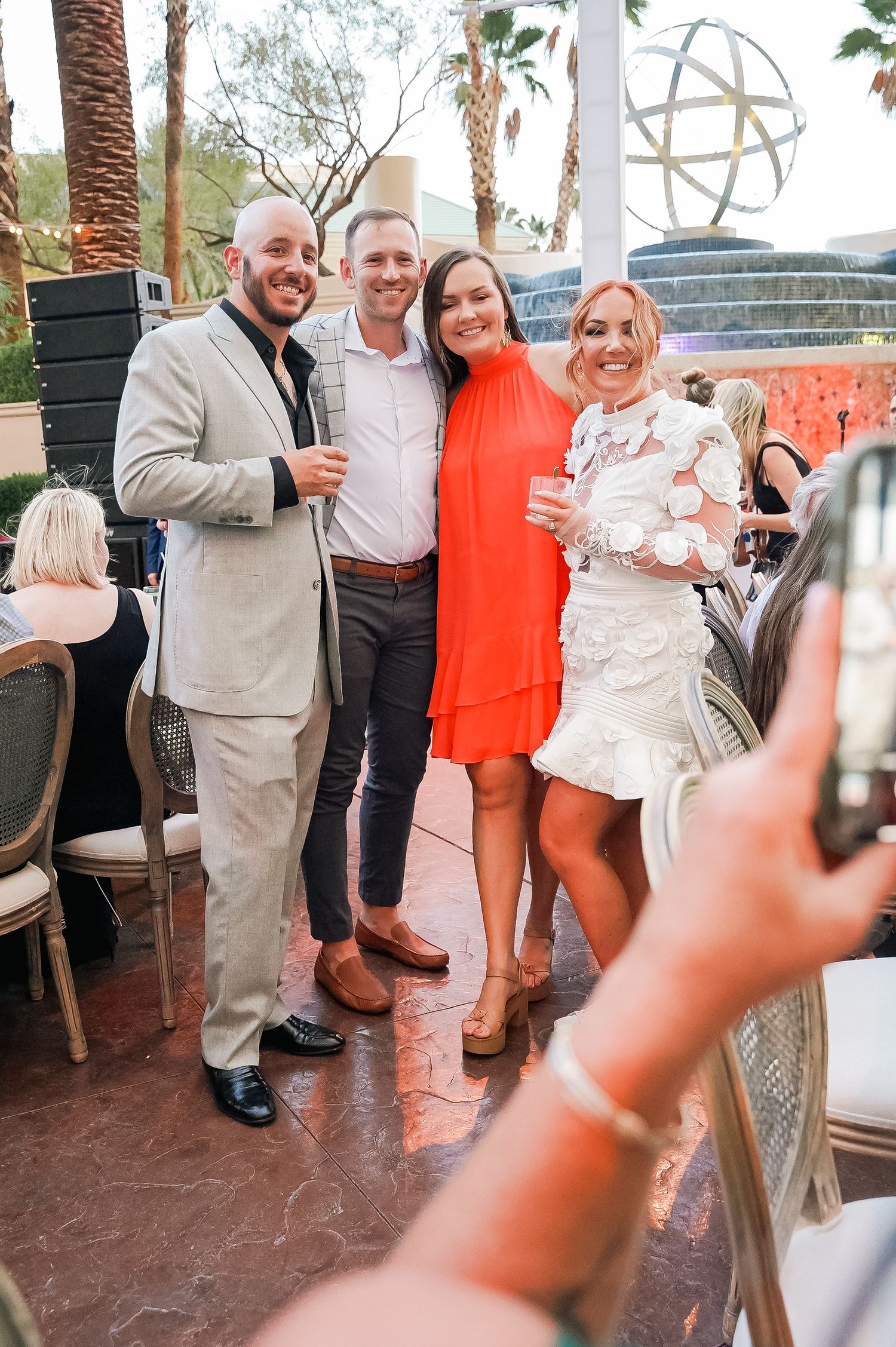 Wedding guests celebrating on outdoor patio with palm trees.