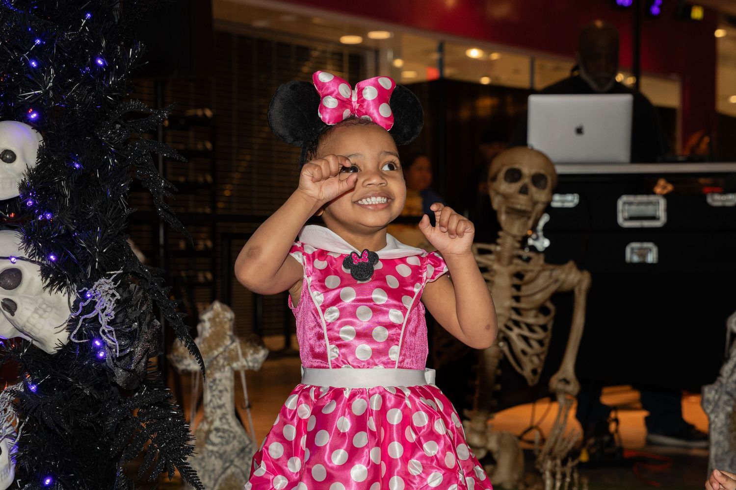 Halloween decorations with skeletons and pink bows in dimly lit space.