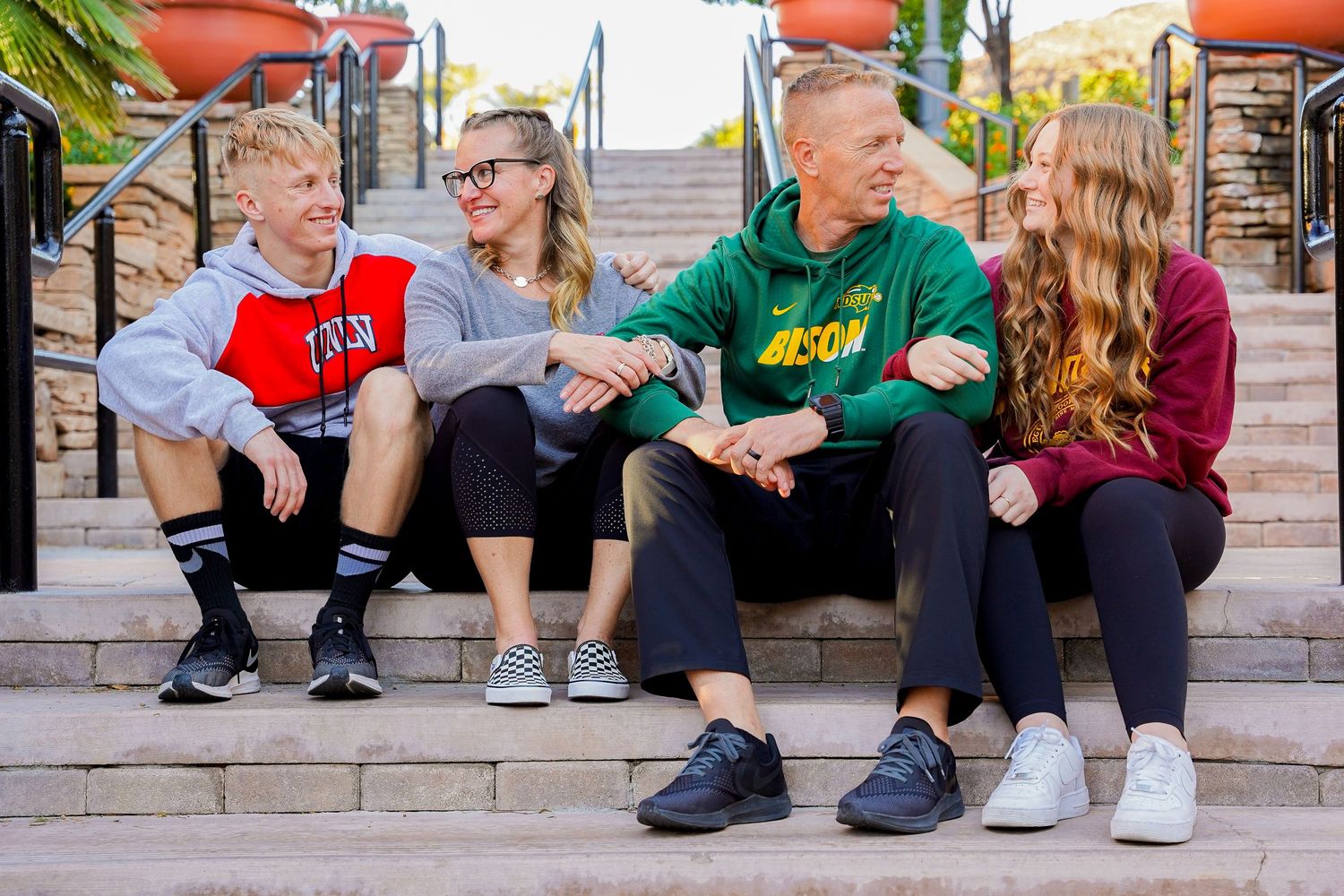 A casual group conversation on outdoor steps with people wearing college branded clothing.