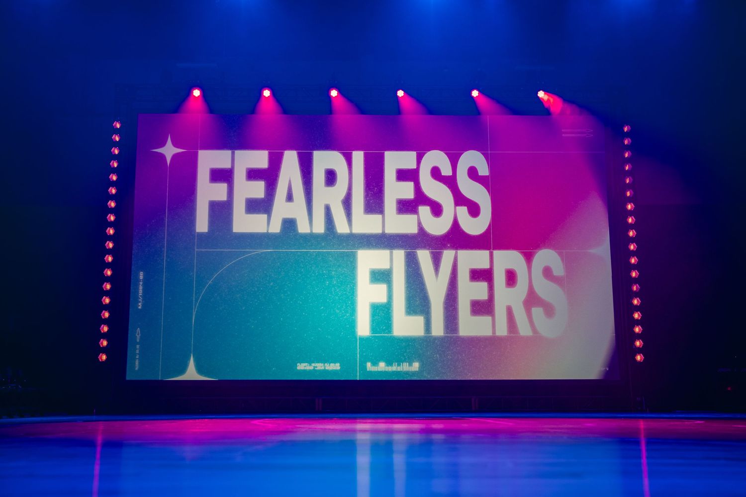 Indoor sports venue with 'Fearless' text displayed on illuminated screens in blue and pink tones.