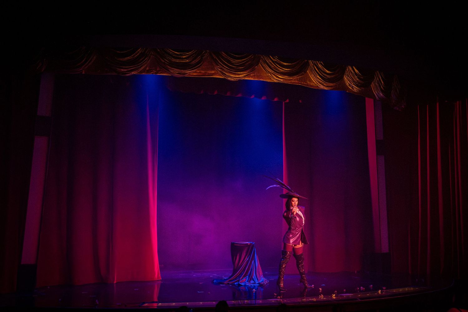 Theatrical stage performance with dramatic purple and red lighting effects.