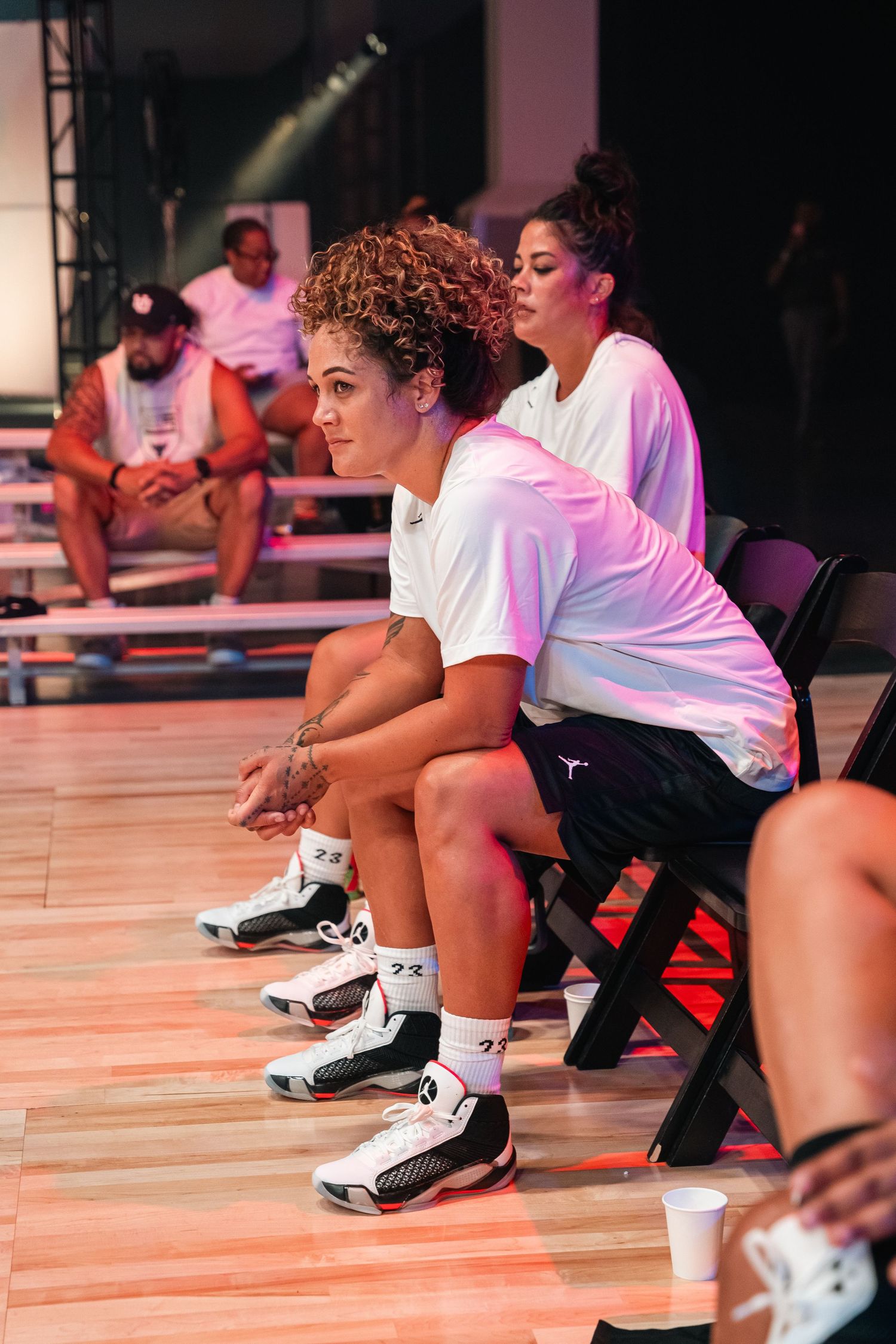Athletes taking a break on courtside benches during basketball practice.