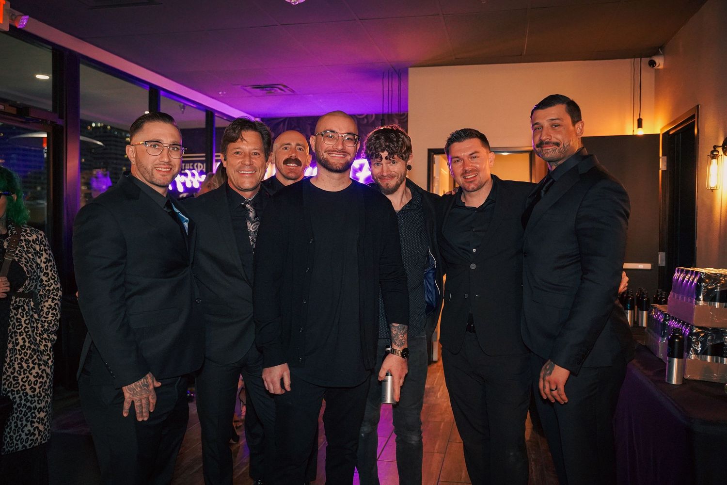 Group of men in black suits and formal attire posing at an evening event.