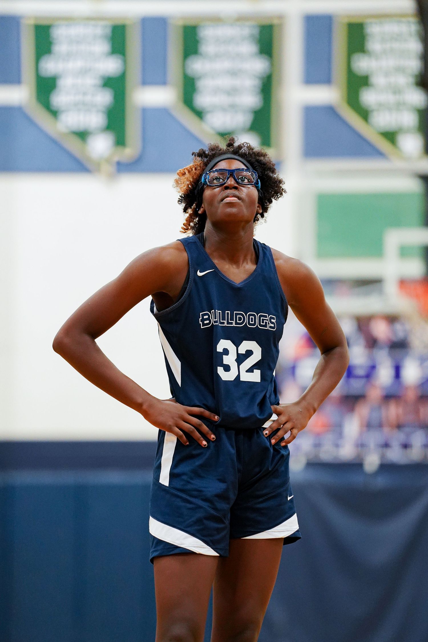 Basketball player in navy Bulldogs jersey stretches during outdoor warmup.