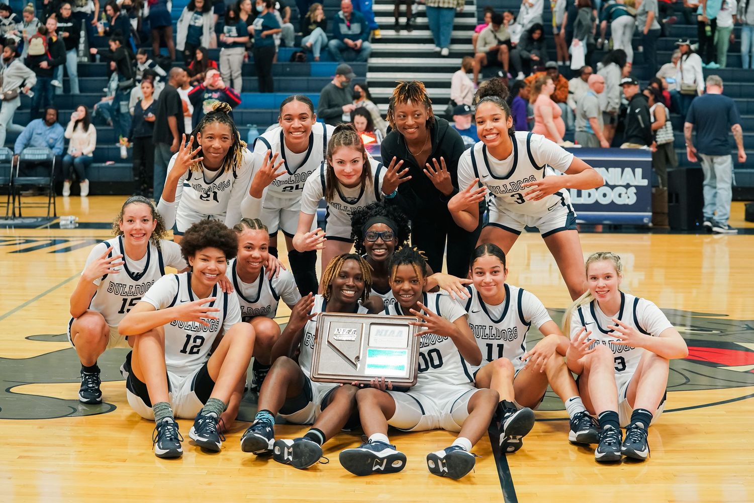 Team players sit together on a basketball court during a game break.