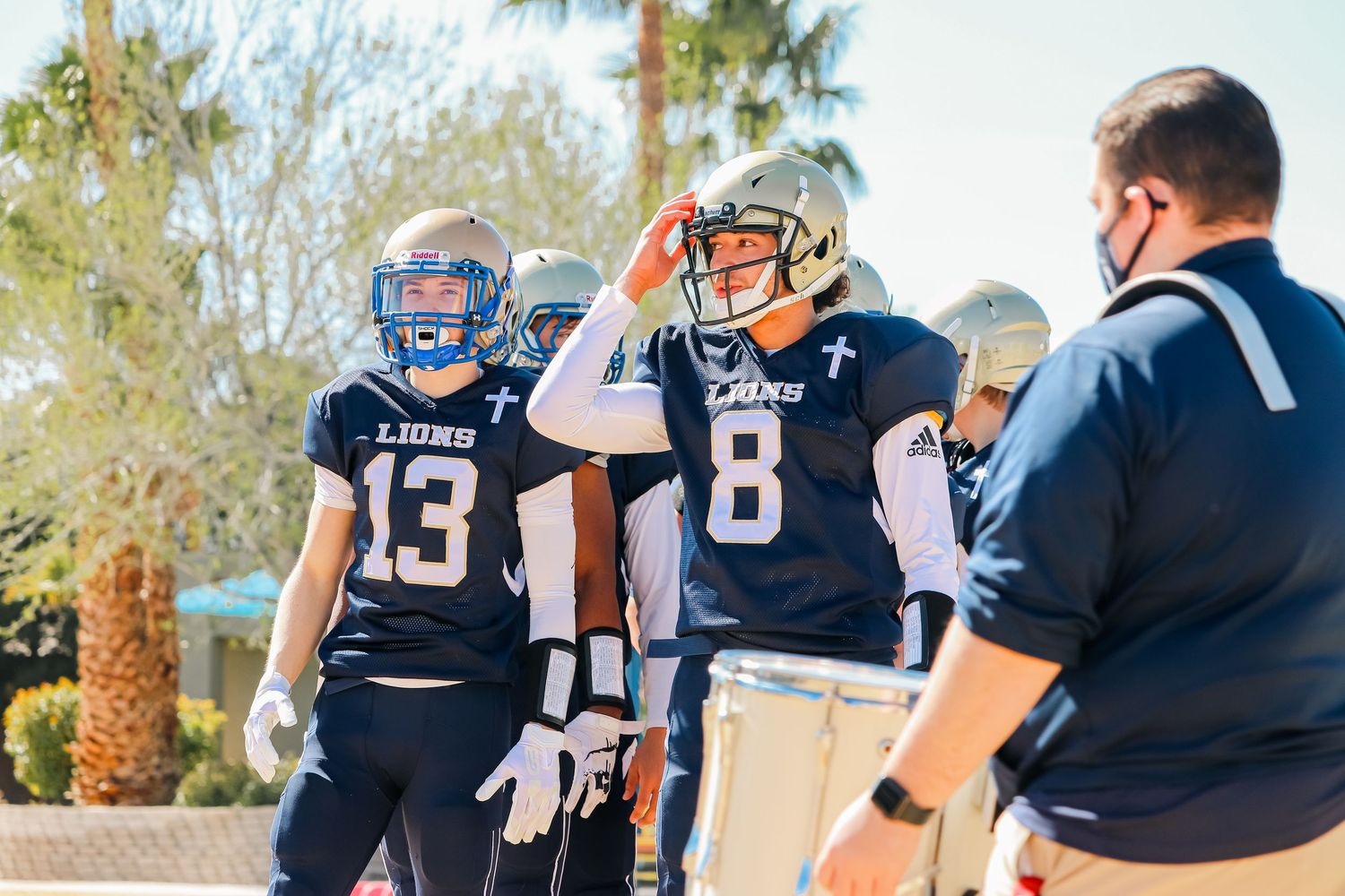 Football team members in navy uniforms gathered on the sidelines.