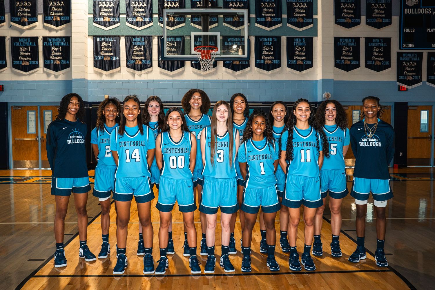 Girls basketball team in blue uniforms poses together on court.