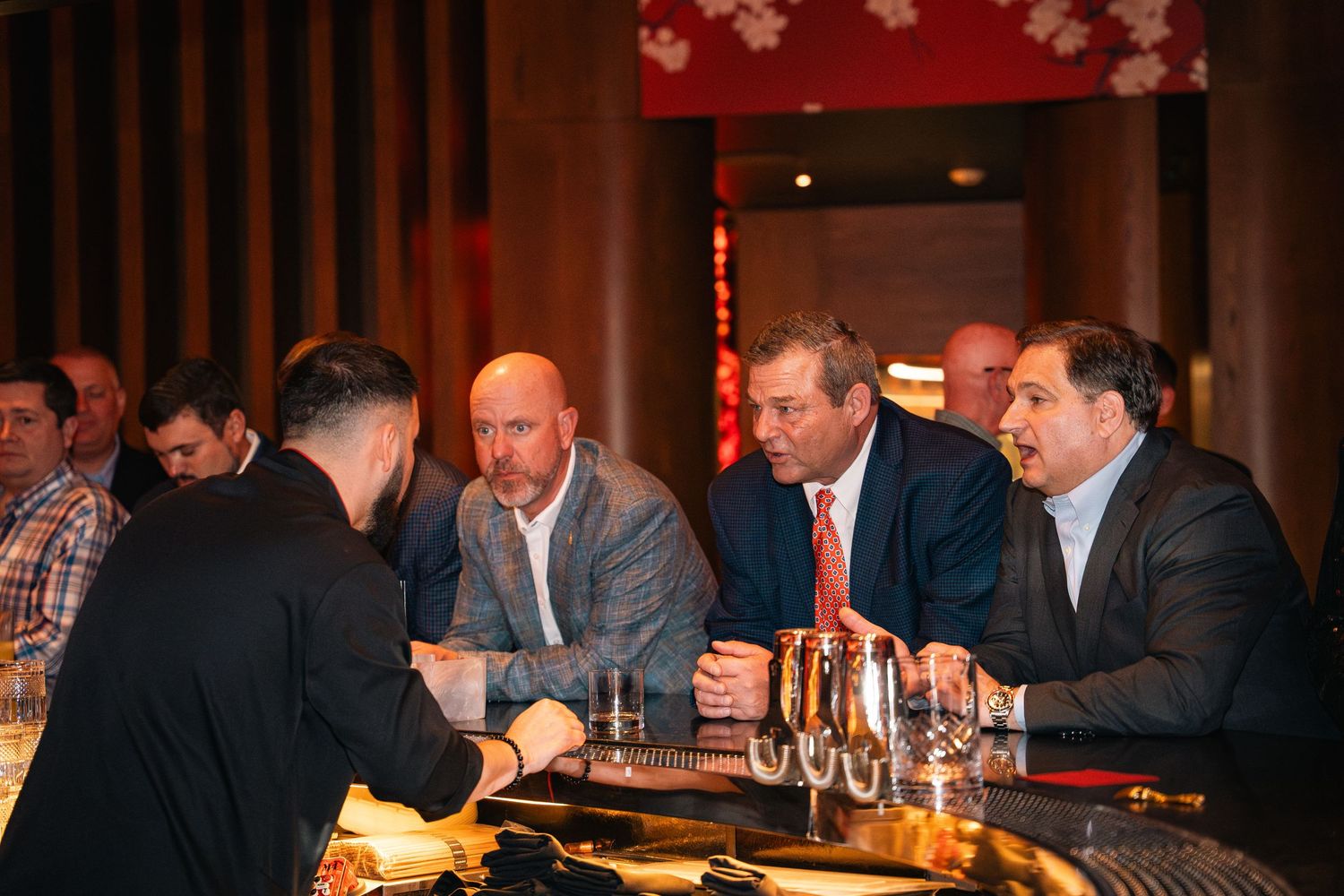 Business professionals seated at a bar having drinks and engaged in conversation.