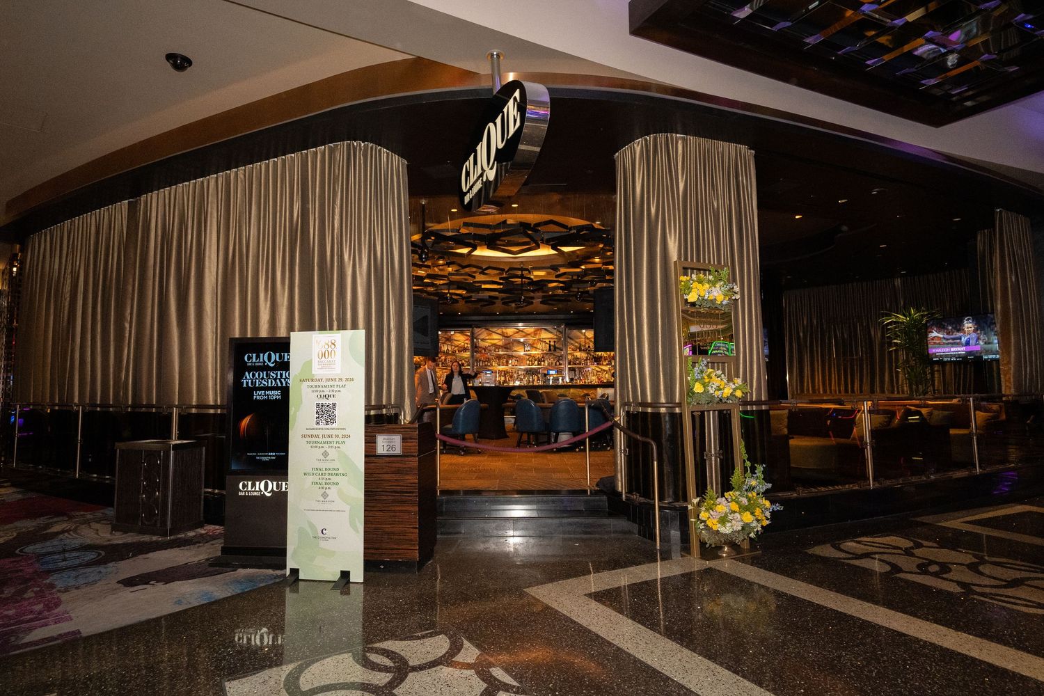 Upscale casino entrance with dramatic curtains and wood paneling in low lighting.