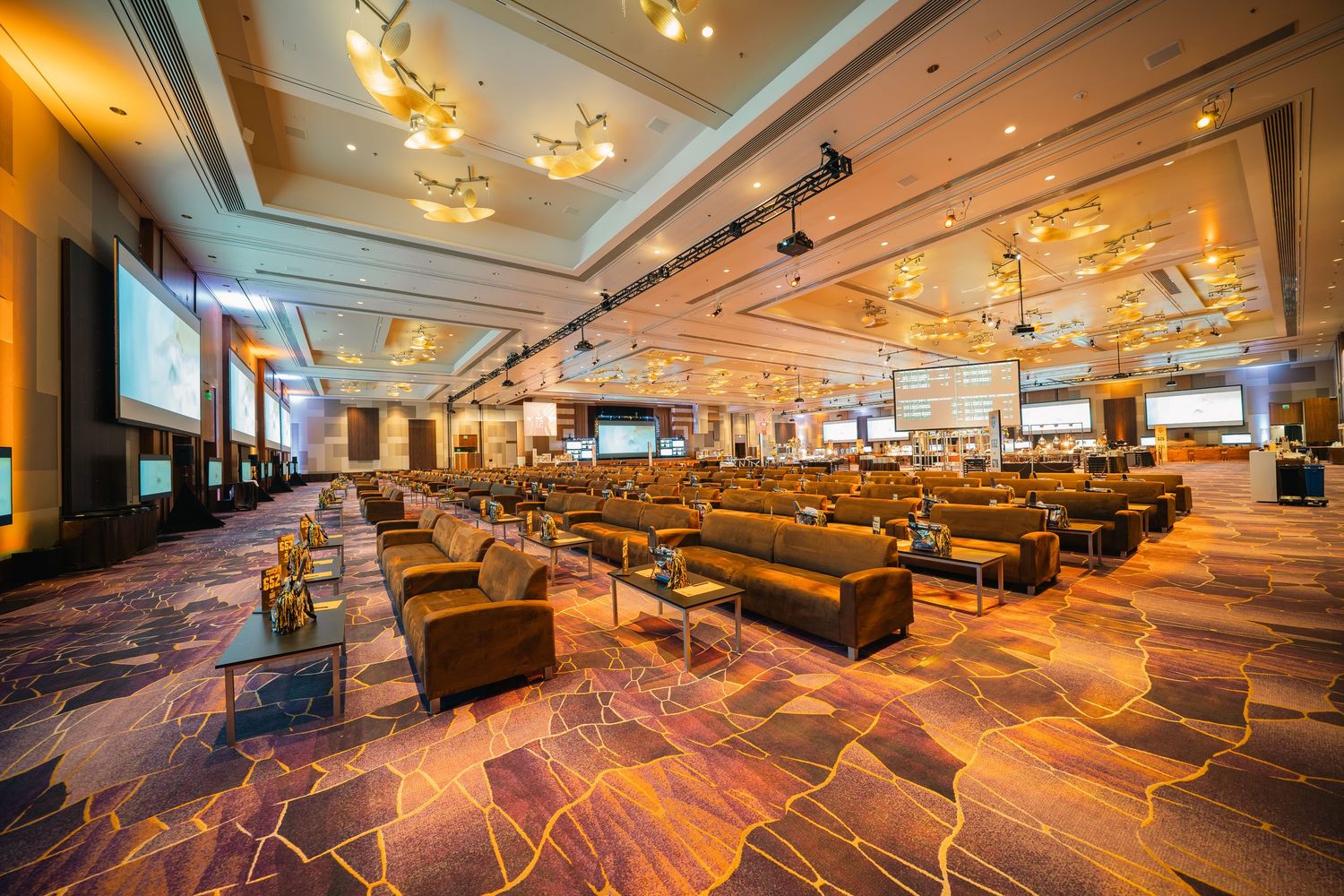 Casino gaming area with orange-tinted lighting and geometric patterned carpeting throughout.