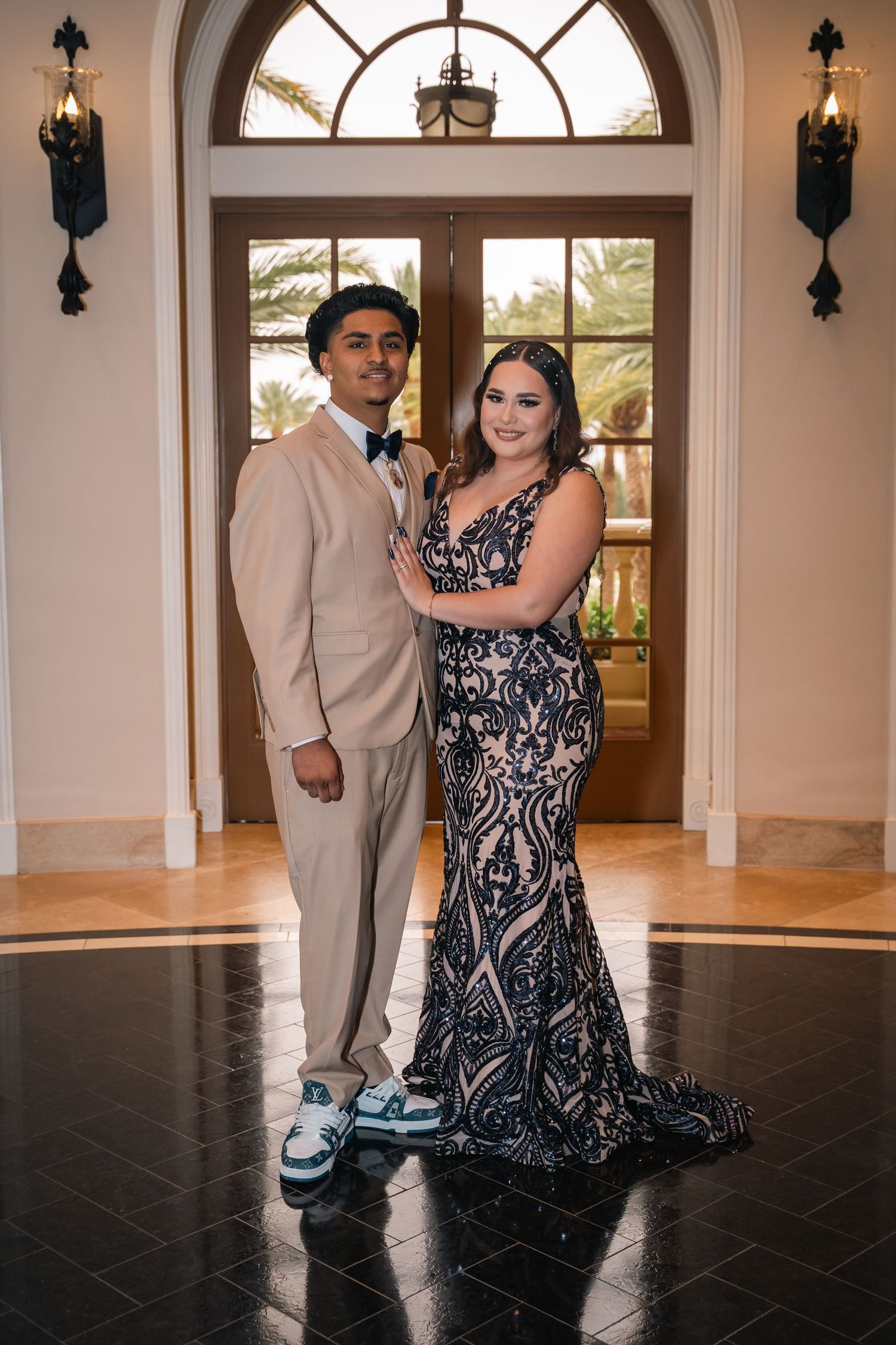 Formal-dressed couple dancing in an elegant ballroom with arched windows.