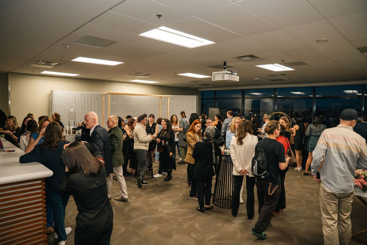 Large crowd mingles at indoor corporate networking event.