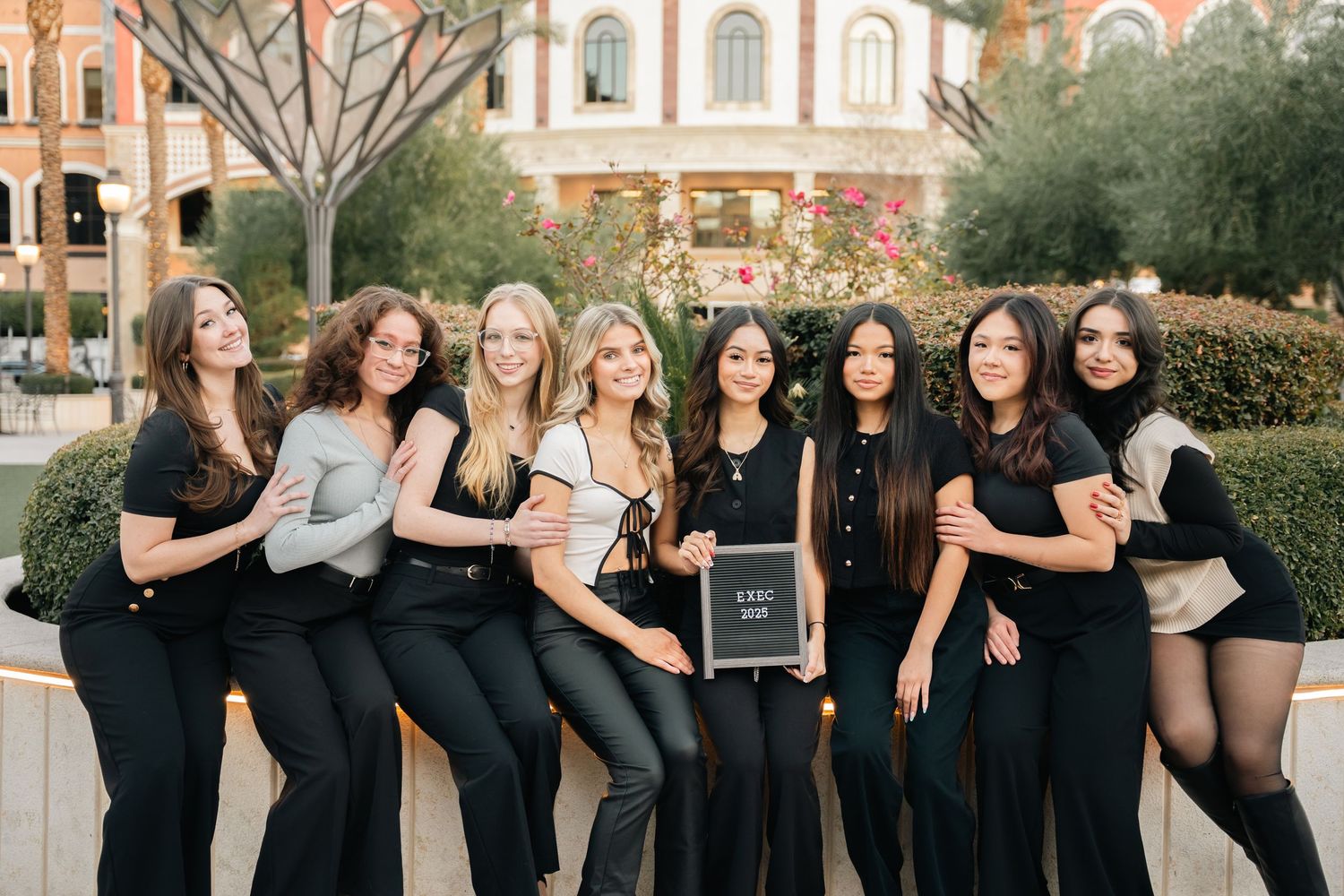 Group portrait of friends in coordinated black outfits gathered outside.