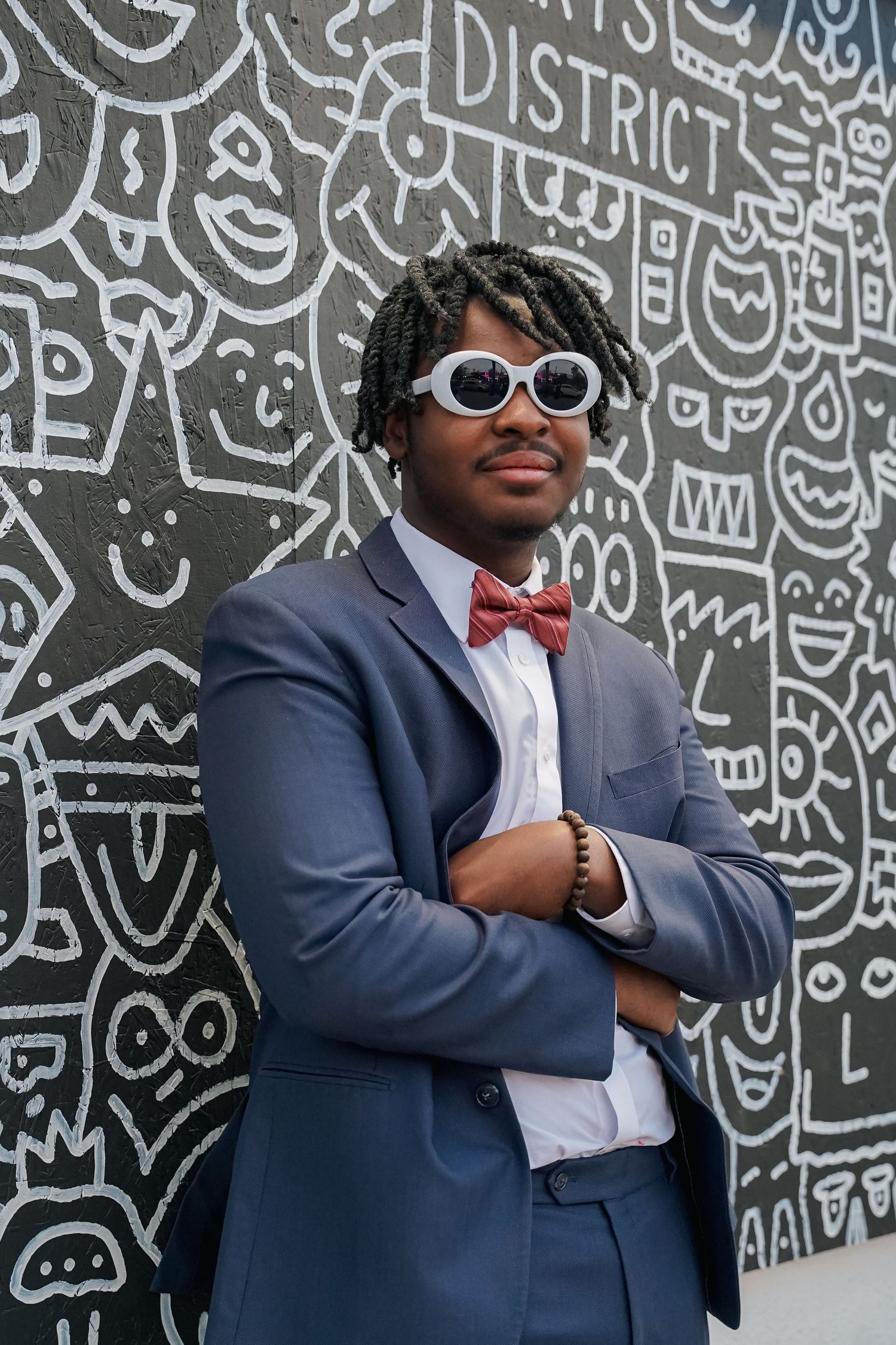 Stylish men in suits pose against a wall covered in black and white graffiti art.