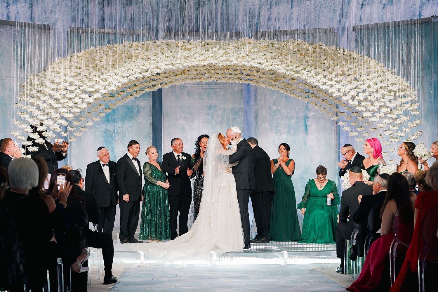 Elegant wedding ceremony under a crystal-adorned arch with emerald and red color scheme.