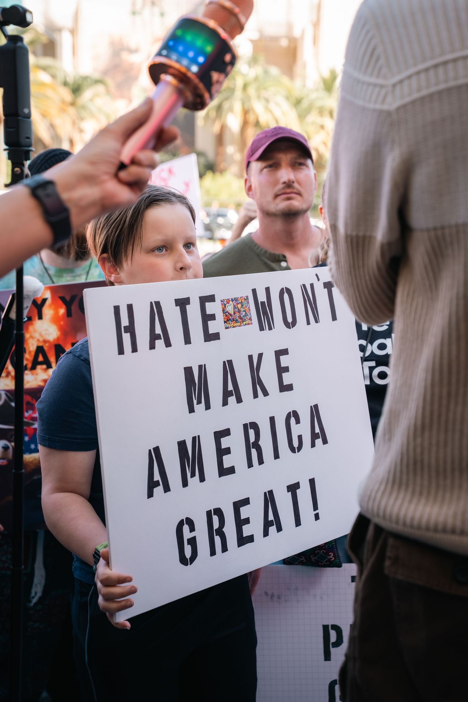 Protesters holding signs that read 'Hate won't make America great' at a demonstration.