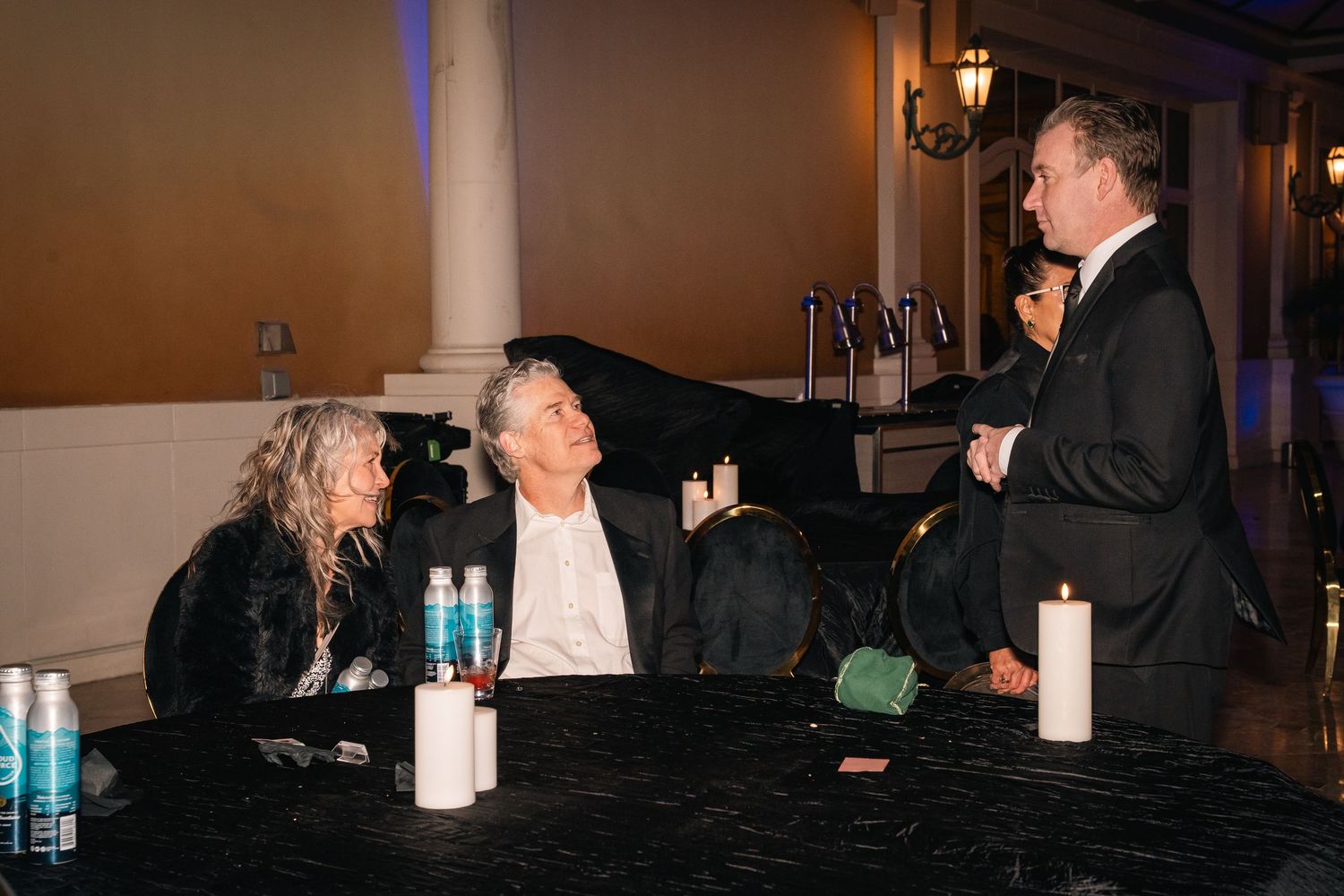 Evening networking event shows attendees engaged in conversation at a round table.