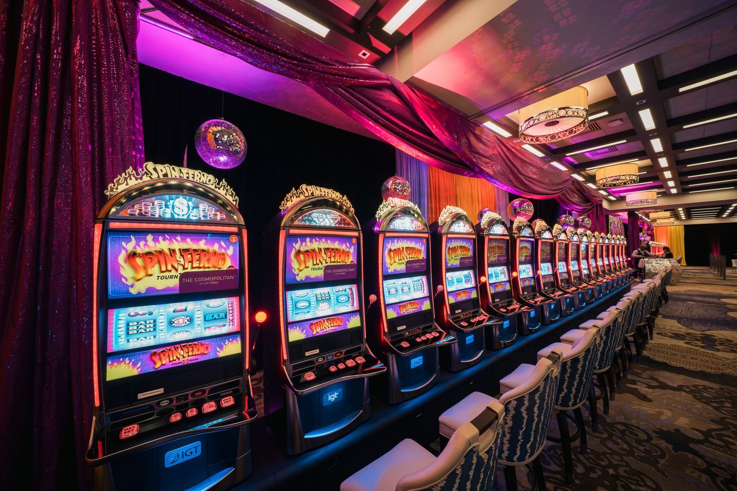 Row of illuminated slot machines with purple ambient lighting in a casino gaming area.