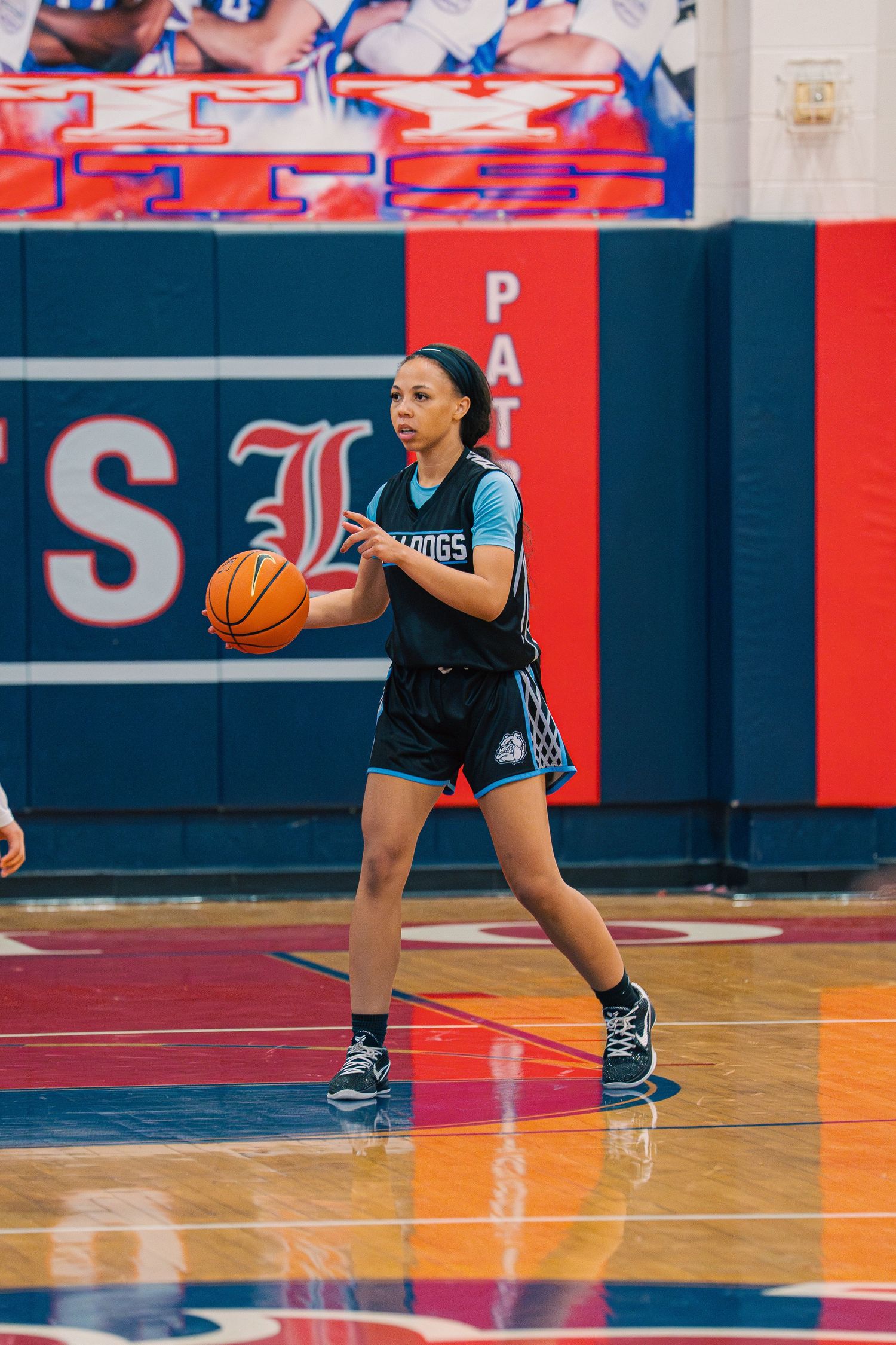 Player dribbles basketball on colorful court with patriotic design in background.