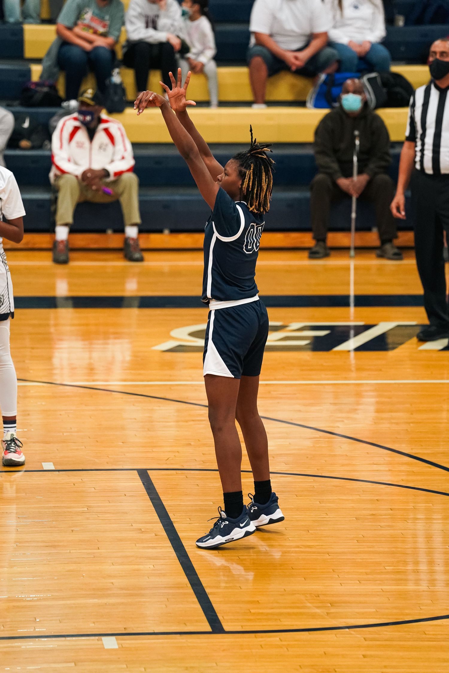 Basketball players in navy and white uniforms positioned on court during game play.