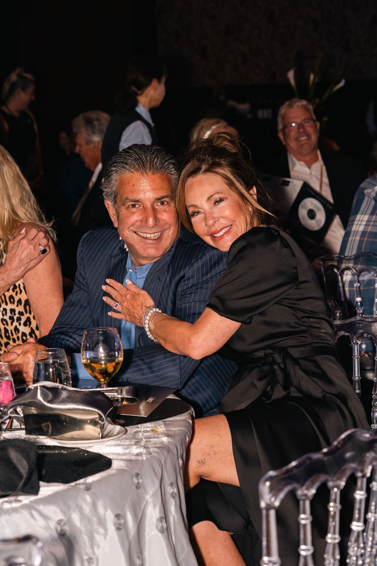 Couple enjoying dinner together at an elegant event with wine glasses and formal table settings.