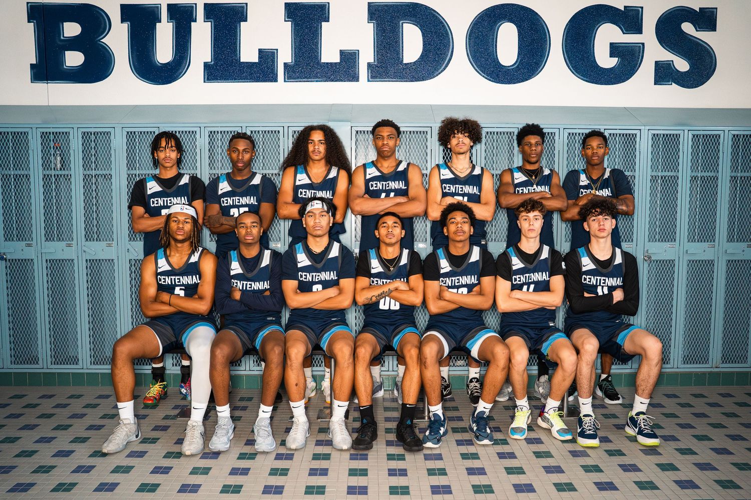 Centennial Bulldogs basketball team sits for group photo in front of blue lockers.