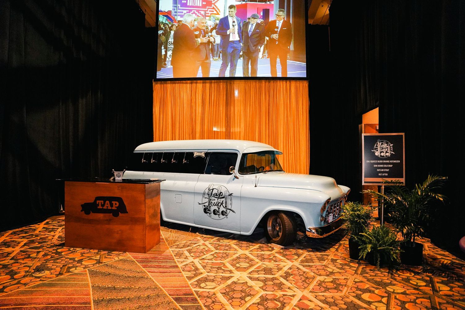 Classic white vintage car display in an event space with orange ambient lighting.