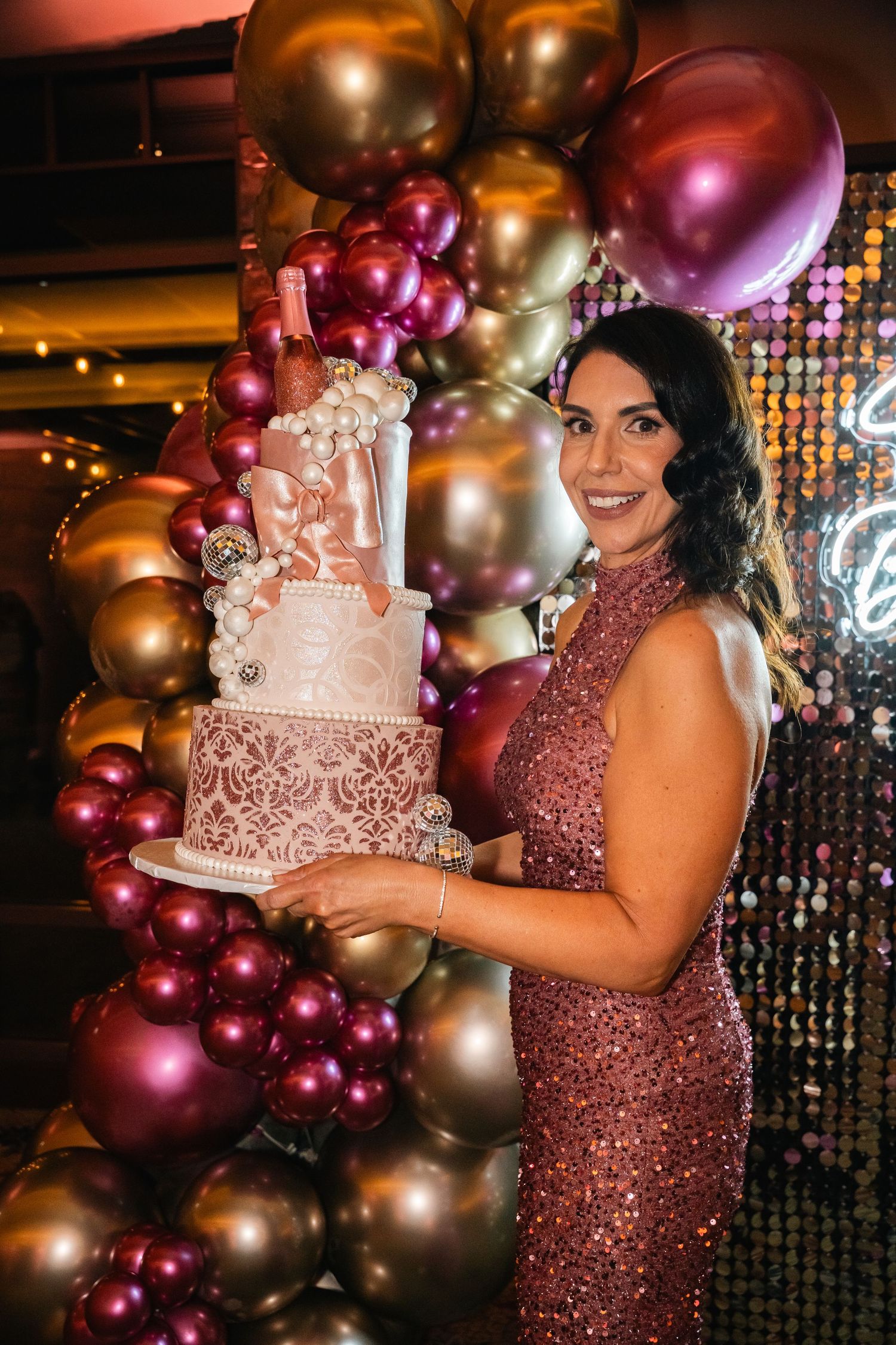 Elegant birthday celebration with metallic balloons and a detailed pink lace cake.