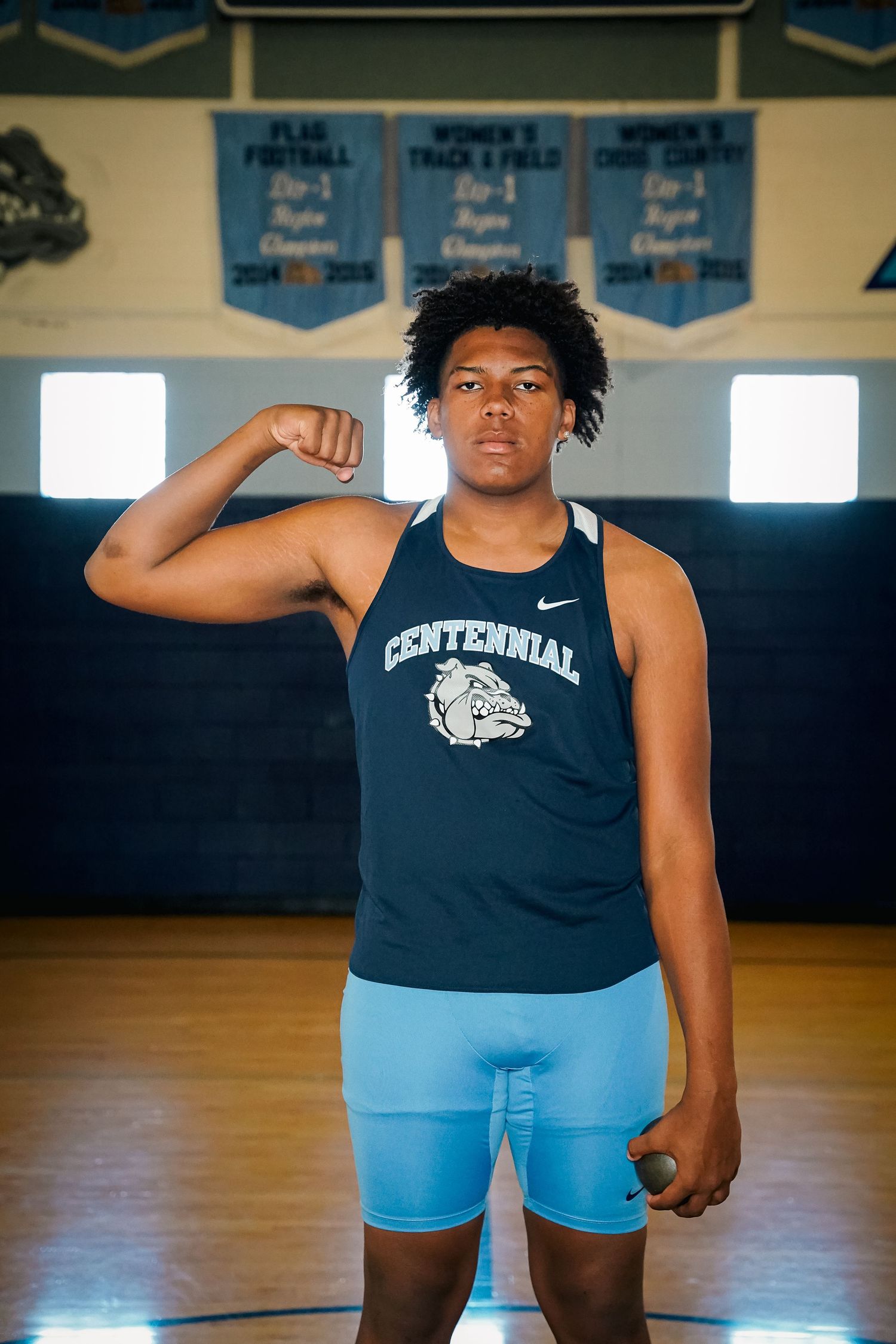 Indoor portrait of athlete in navy Centennial tank top and blue shorts in gymnasium.
