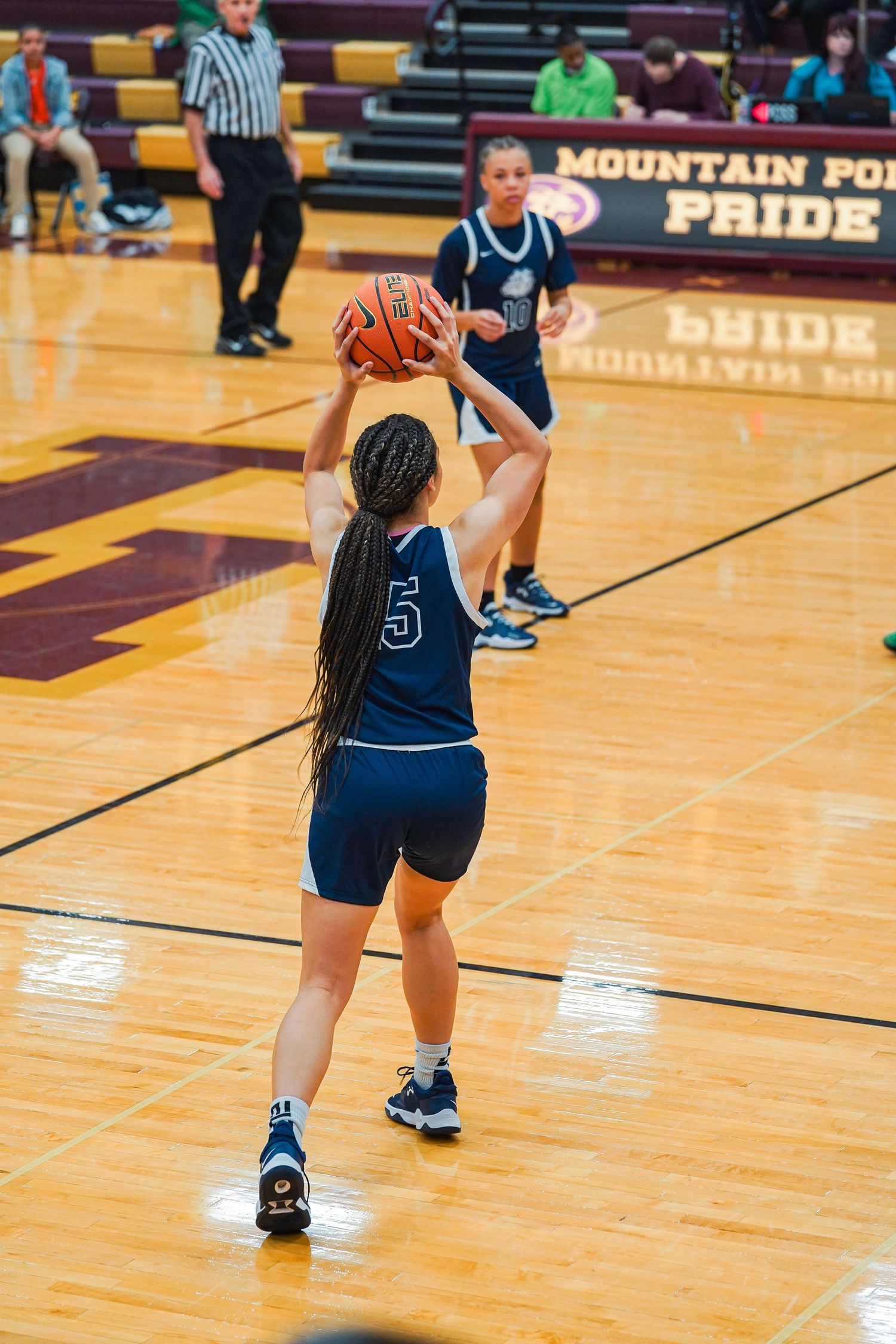 Basketball players in navy uniforms practice dribbling skills during team training.